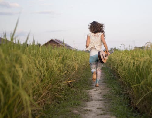 Girl running through rice paddy at a yoga retreats Thailand
